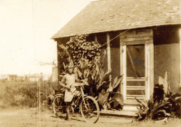12 year old Bobby Wells on a borrowed bicycle in front of the family home in Port Isabel. (1935)